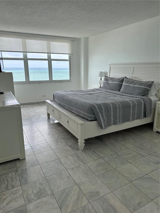 bedroom featuring a textured ceiling and a water view