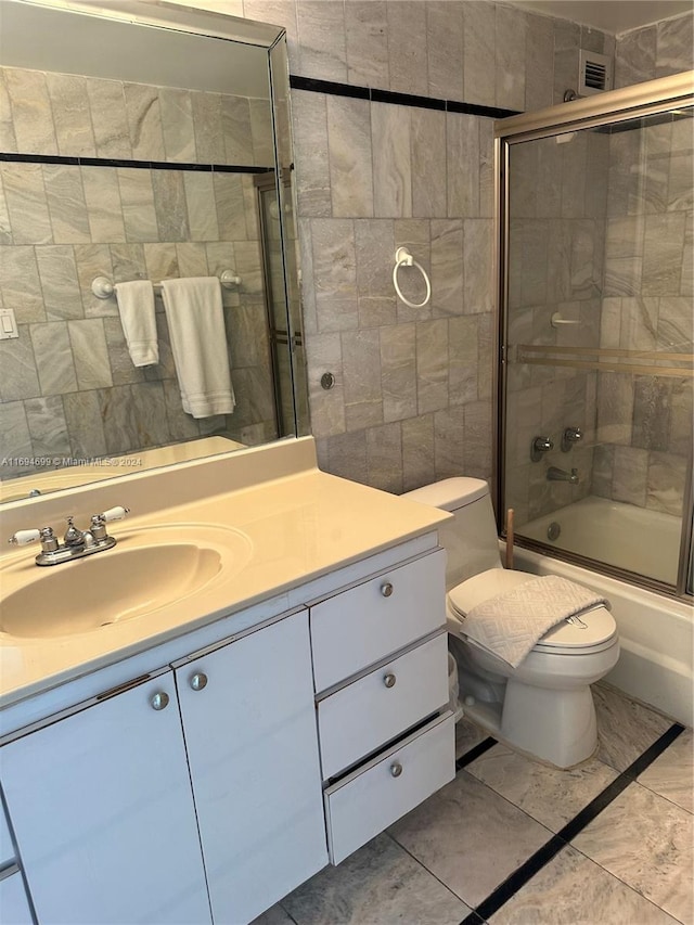 full bathroom featuring shower / bath combination with glass door, tile patterned floors, vanity, and toilet