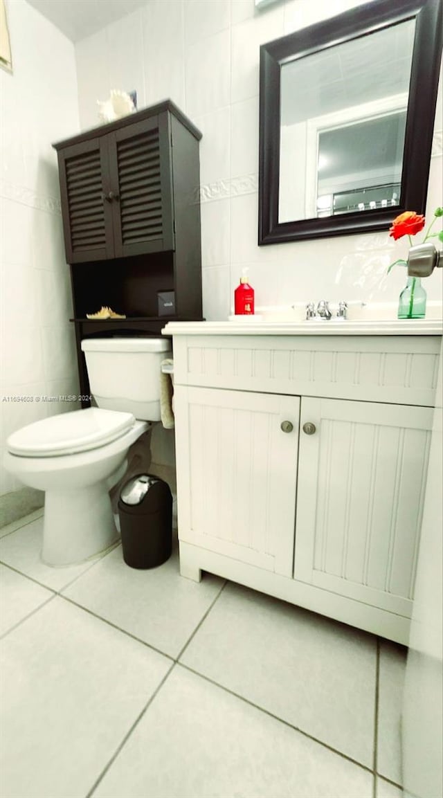 bathroom with tile patterned flooring, vanity, tile walls, and toilet