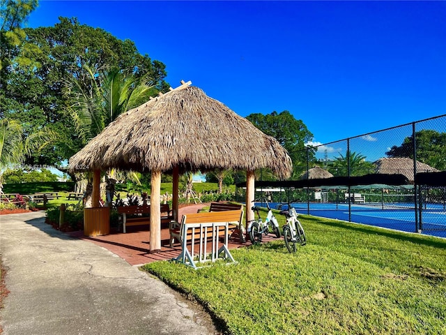 view of property's community featuring a gazebo, a lawn, and tennis court