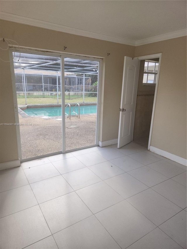 tiled empty room featuring a healthy amount of sunlight and crown molding