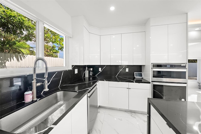 kitchen with white cabinets, decorative backsplash, appliances with stainless steel finishes, and dark stone counters