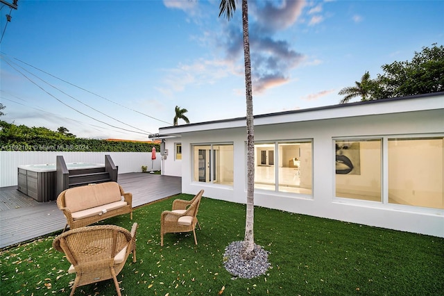 back of house featuring a yard, a deck, and a hot tub