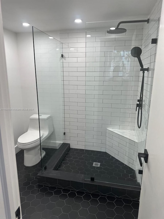 bathroom featuring tiled shower, tile patterned flooring, and toilet