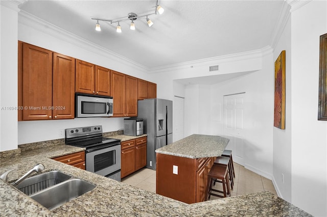 kitchen featuring a kitchen breakfast bar, ornamental molding, stainless steel appliances, sink, and a kitchen island