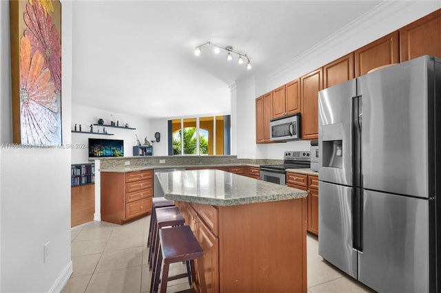 kitchen with a kitchen bar, kitchen peninsula, stainless steel appliances, light tile patterned floors, and a kitchen island