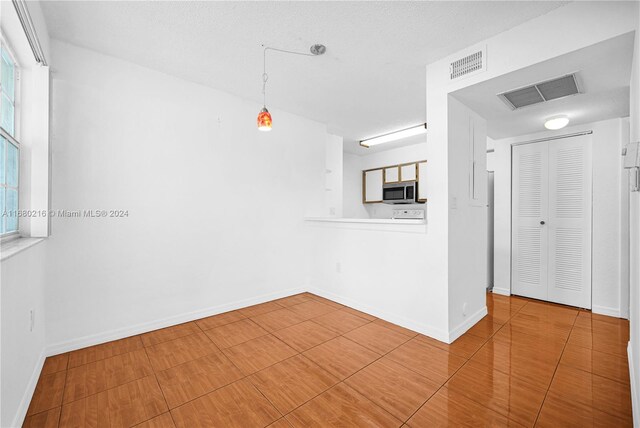 unfurnished room with tile patterned flooring and a textured ceiling