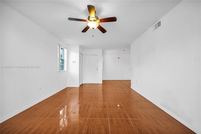 empty room with a textured ceiling and ceiling fan