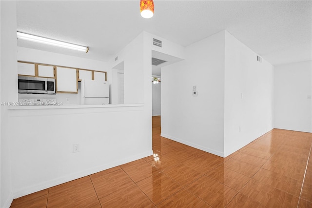 unfurnished living room featuring a textured ceiling and tile patterned floors