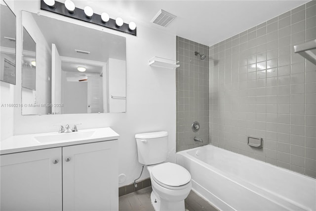 full bathroom featuring vanity, tiled shower / bath, and toilet