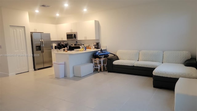 kitchen with appliances with stainless steel finishes, white cabinets, light tile patterned flooring, and kitchen peninsula