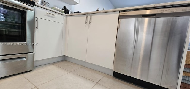 kitchen with stainless steel dishwasher, double wall oven, white cabinets, and light tile patterned floors