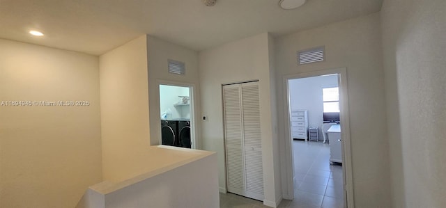 hall featuring independent washer and dryer and light tile patterned floors