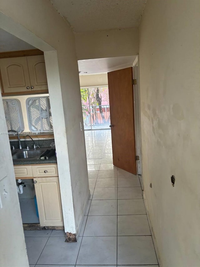 corridor featuring light tile patterned floors and sink