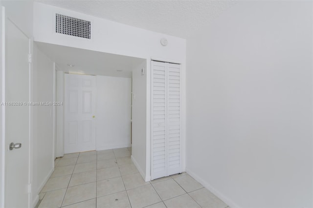 hall with light tile patterned floors and a textured ceiling