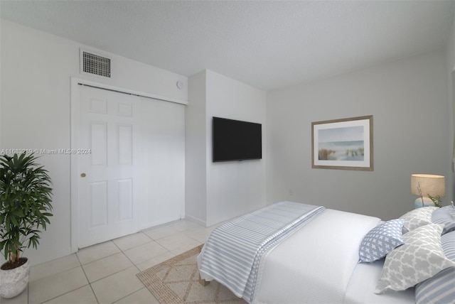 bedroom with light tile patterned floors and a textured ceiling