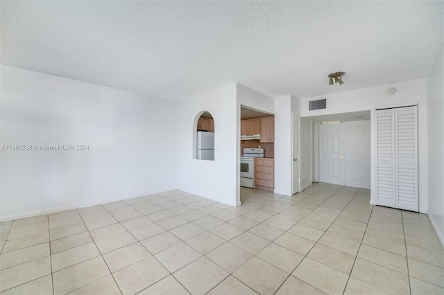 spare room featuring light tile patterned floors and a textured ceiling