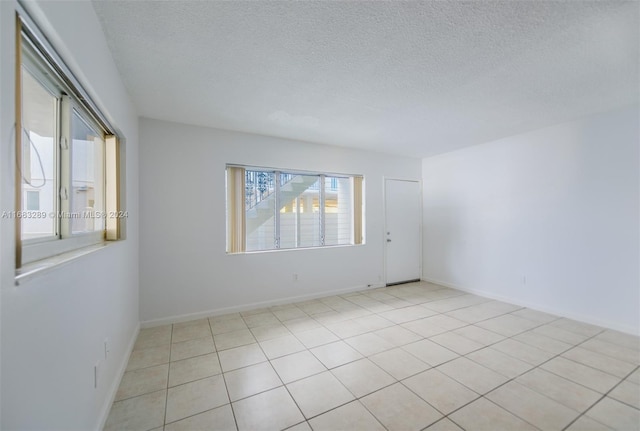 spare room with light tile patterned floors and a textured ceiling