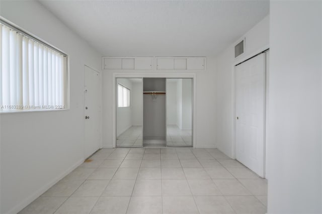 unfurnished bedroom with light tile patterned floors, a textured ceiling, and a closet