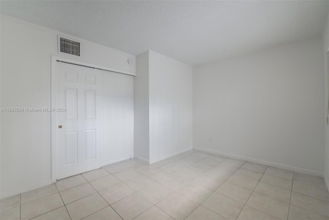 unfurnished bedroom featuring light tile patterned floors, a textured ceiling, and a closet