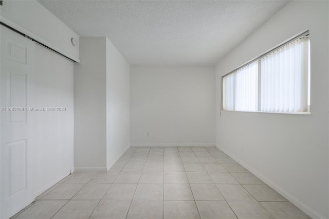 tiled empty room featuring a textured ceiling