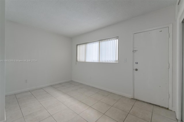 entryway with light tile patterned floors and a textured ceiling