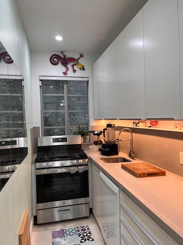 kitchen featuring dishwasher, light tile patterned flooring, sink, gas stove, and white cabinetry