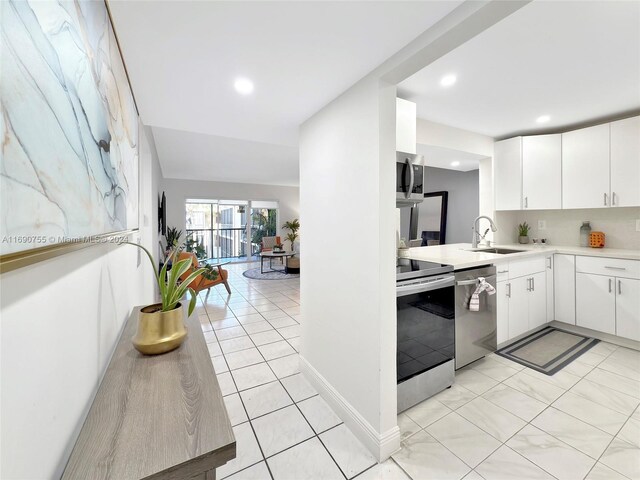 kitchen featuring backsplash, white cabinets, sink, appliances with stainless steel finishes, and light tile patterned flooring