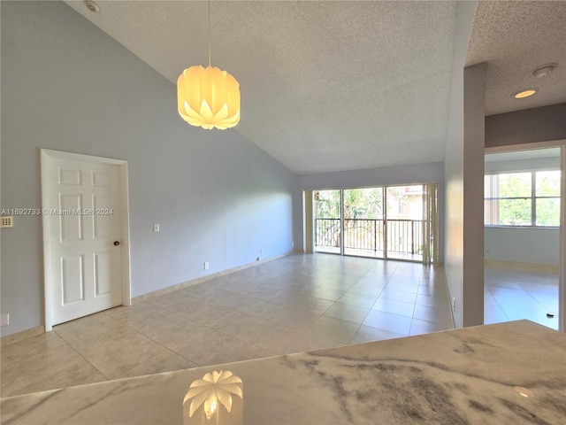 tiled spare room featuring high vaulted ceiling and a textured ceiling