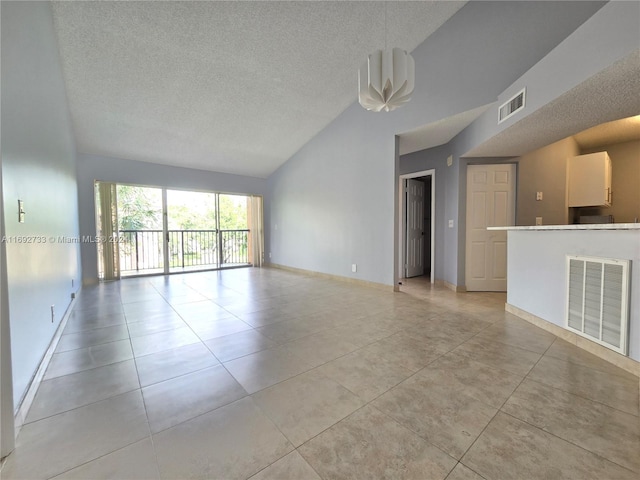 tiled empty room with a textured ceiling and high vaulted ceiling