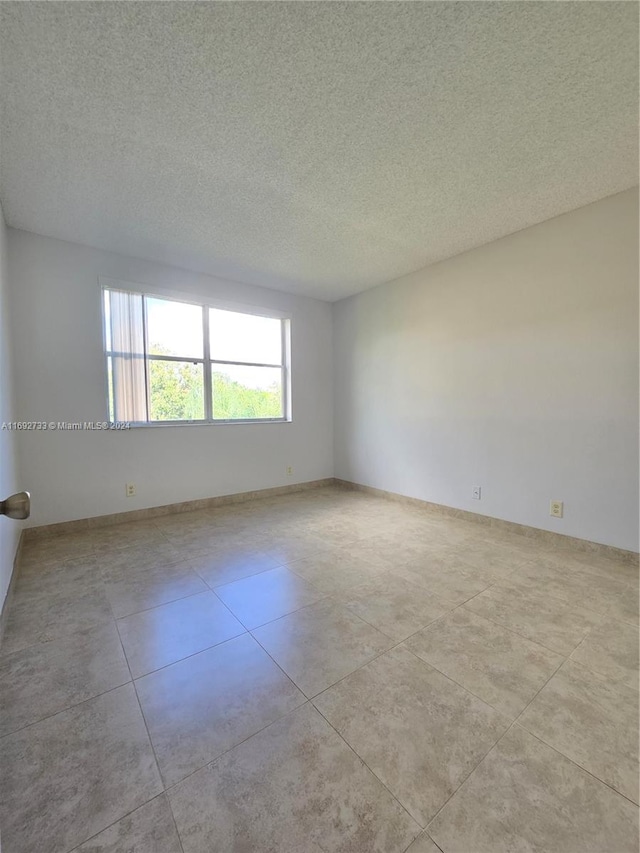 unfurnished room featuring light tile patterned flooring and a textured ceiling