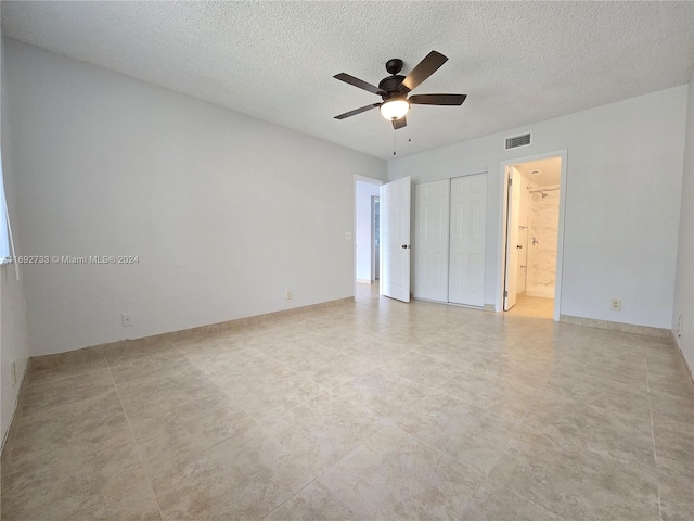 unfurnished bedroom with a textured ceiling, ceiling fan, light tile patterned floors, and ensuite bathroom