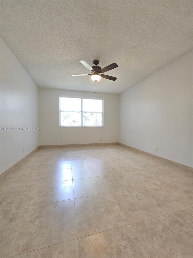 tiled spare room featuring a textured ceiling and ceiling fan