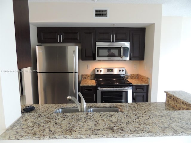 kitchen featuring light stone countertops, sink, and appliances with stainless steel finishes