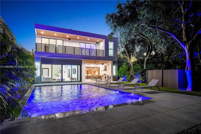 back of property featuring a balcony, a patio area, and a fenced in pool