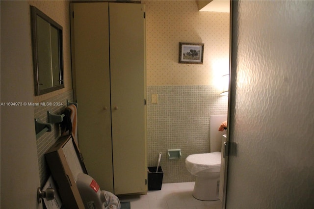 bathroom with tile patterned flooring, tile walls, and toilet