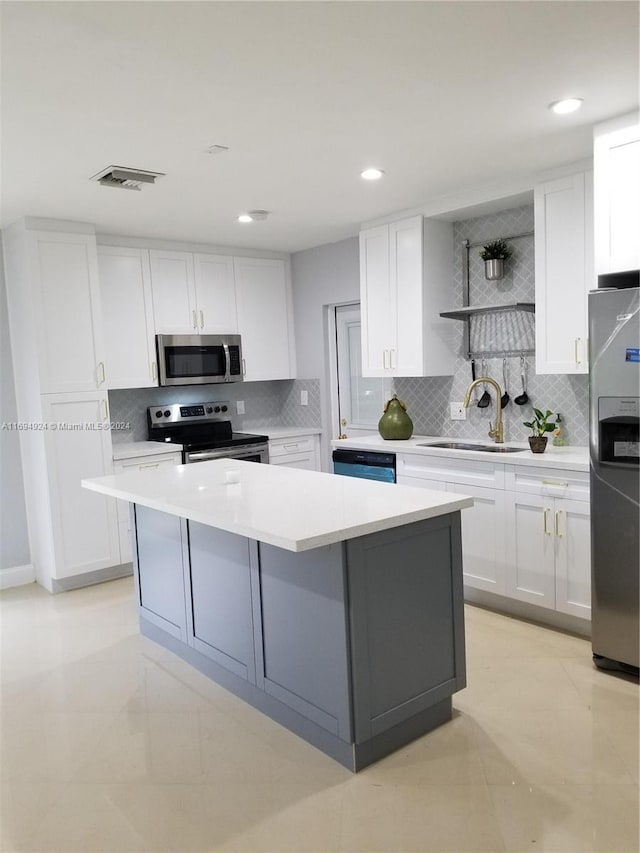 kitchen featuring decorative backsplash, white cabinetry, a kitchen island, and appliances with stainless steel finishes