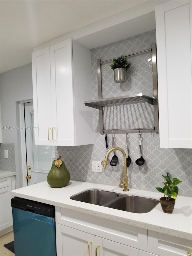 kitchen with stainless steel dishwasher, backsplash, white cabinetry, and sink