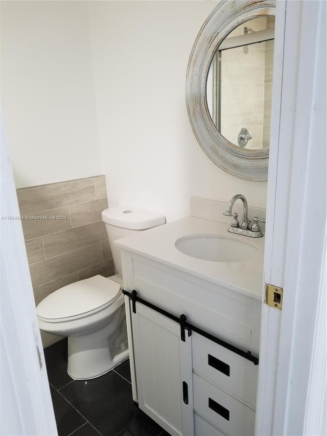 bathroom with tile patterned flooring, vanity, toilet, and tile walls