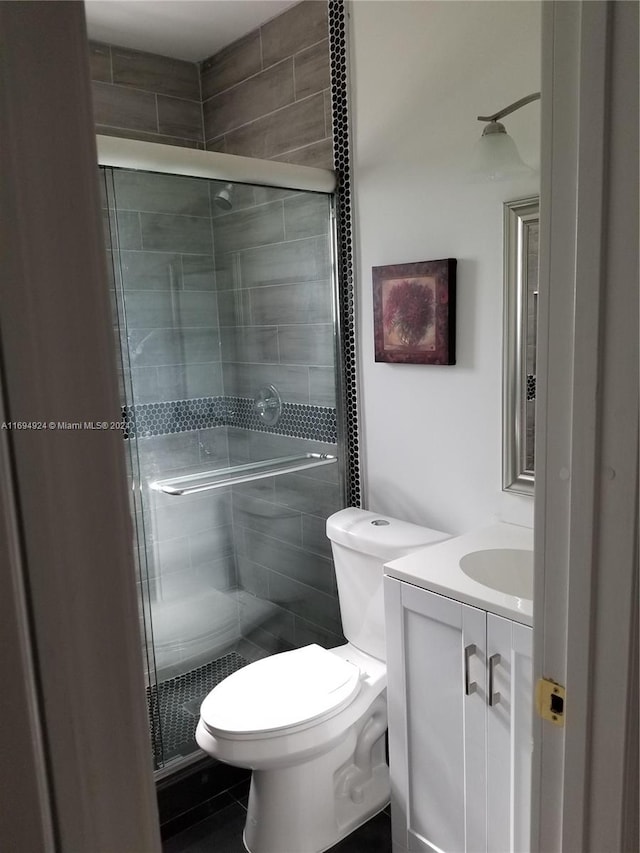 bathroom with tile patterned floors, vanity, toilet, and walk in shower