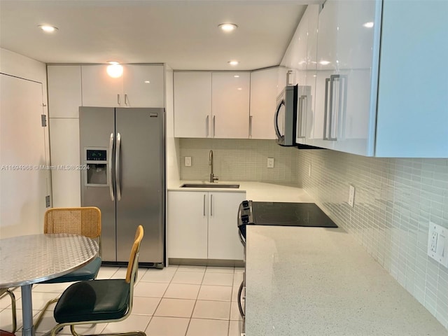 1500 S Ocean Dr Unit 17E, Hollywood, FL 33019 - kitchen with stainless steel appliances, a sink, white cabinets, decorative backsplash, and light stone countertops