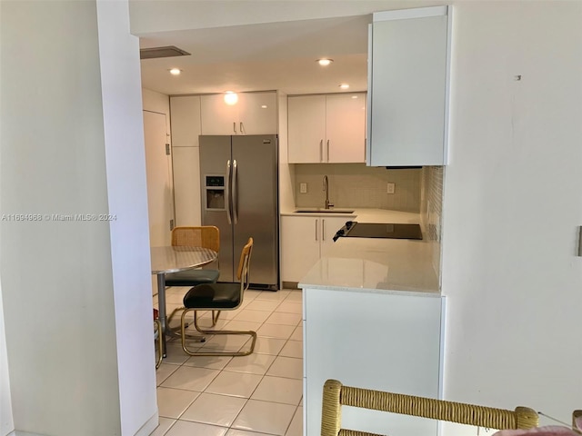 kitchen featuring white cabinets, sink, stainless steel refrigerator with ice dispenser, decorative backsplash, and light tile patterned floors