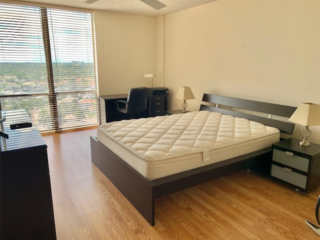 bedroom with ceiling fan, a textured ceiling, and light hardwood / wood-style flooring