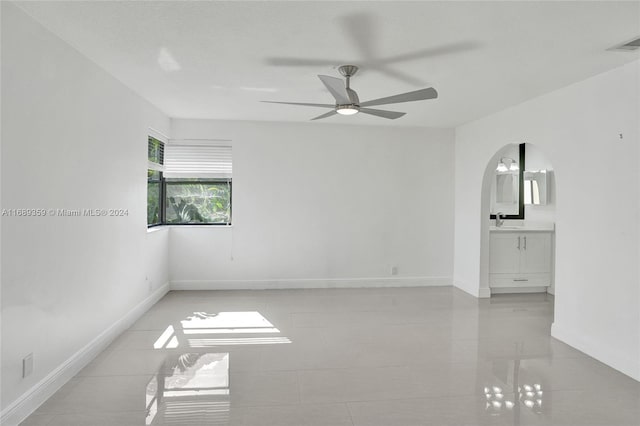 empty room with light tile patterned floors, ceiling fan, and sink