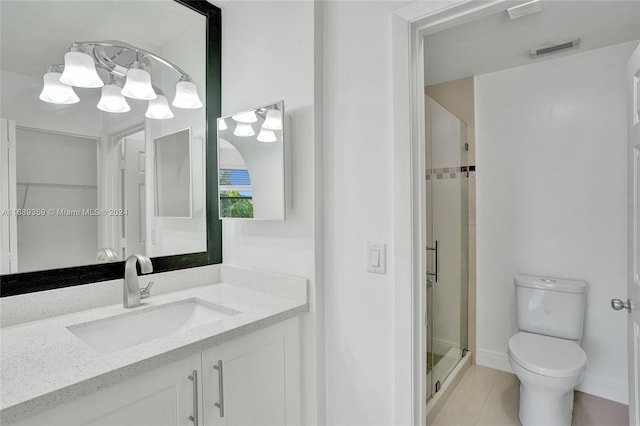 bathroom featuring tile patterned floors, vanity, an enclosed shower, and toilet