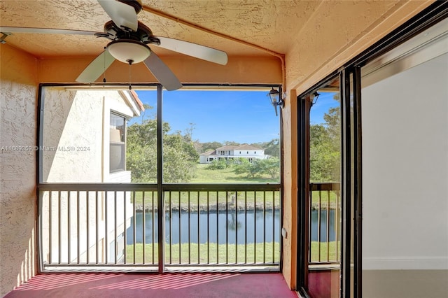 unfurnished sunroom with ceiling fan and a water view