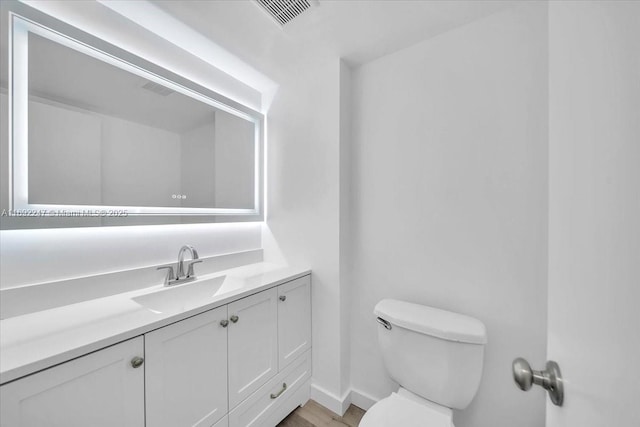 bathroom with toilet, wood-type flooring, and vanity