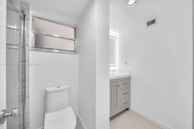 bathroom with toilet, vanity, and a shower with door