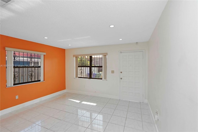 tiled spare room featuring a textured ceiling