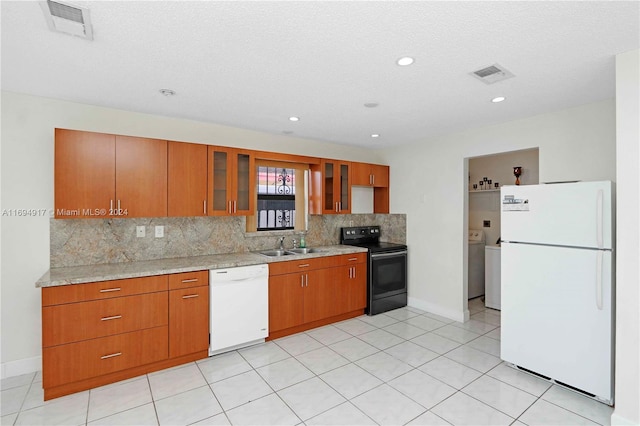 kitchen featuring decorative backsplash, a textured ceiling, white appliances, sink, and washer / clothes dryer